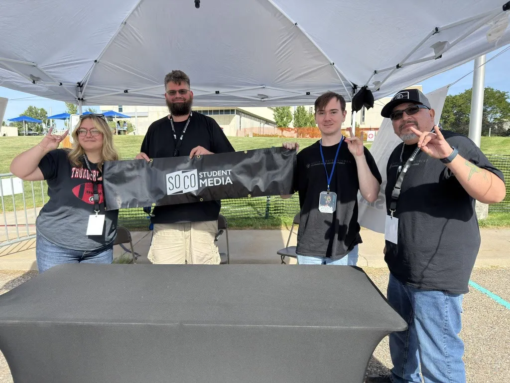 Bear and three teammates holding a SoCo Student Media banner